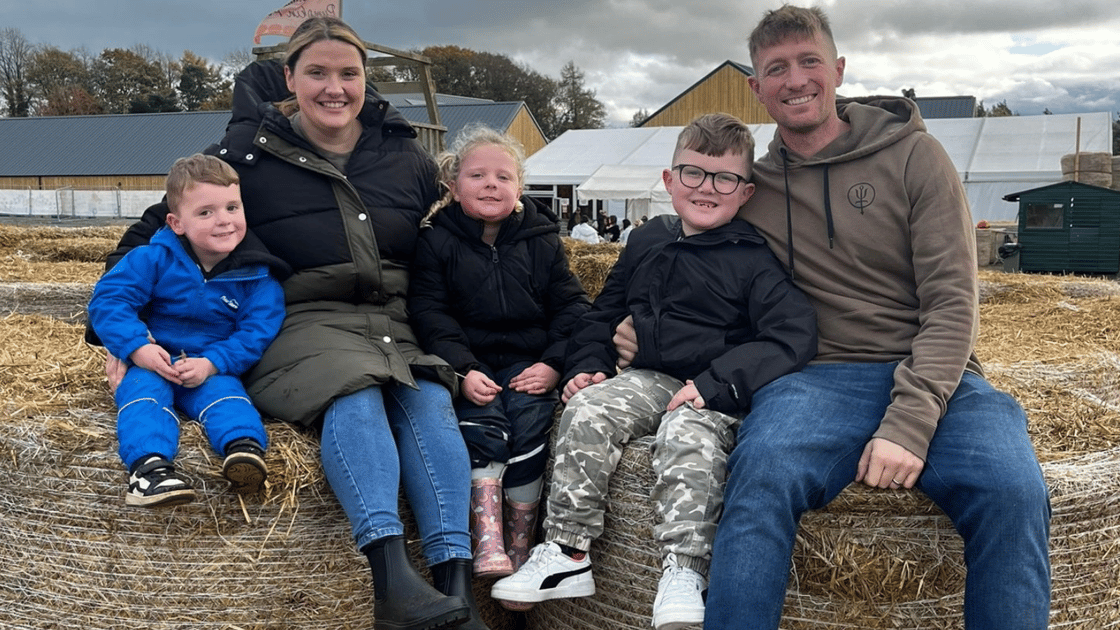 The Tanner-Boyer family is pictured sat on hay bales.